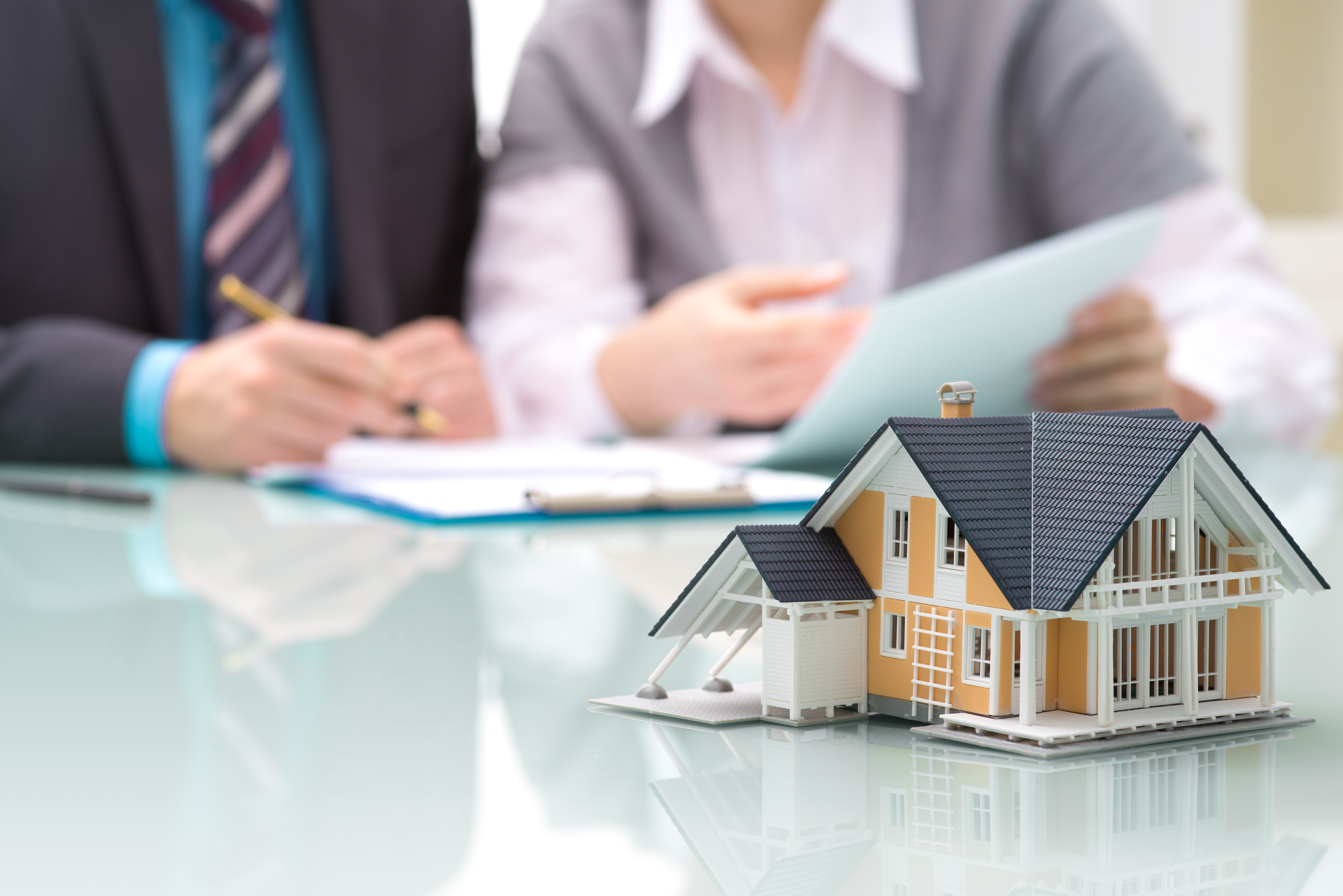 Real estate professionals reviewing a home sale with a model house